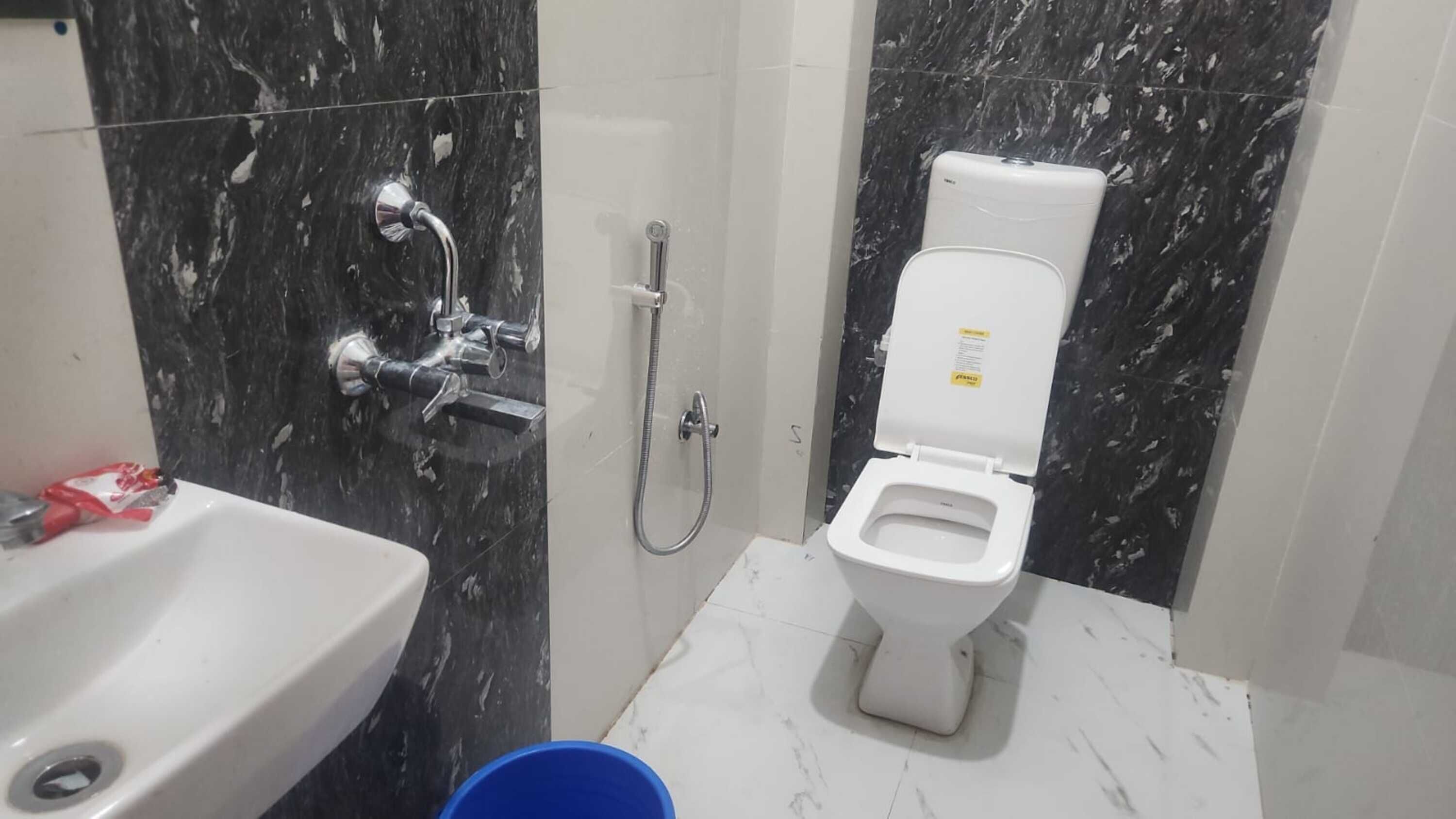 Un baño con lavamanos blanco, inodoro y ducha con cabezal de ducha de mano.