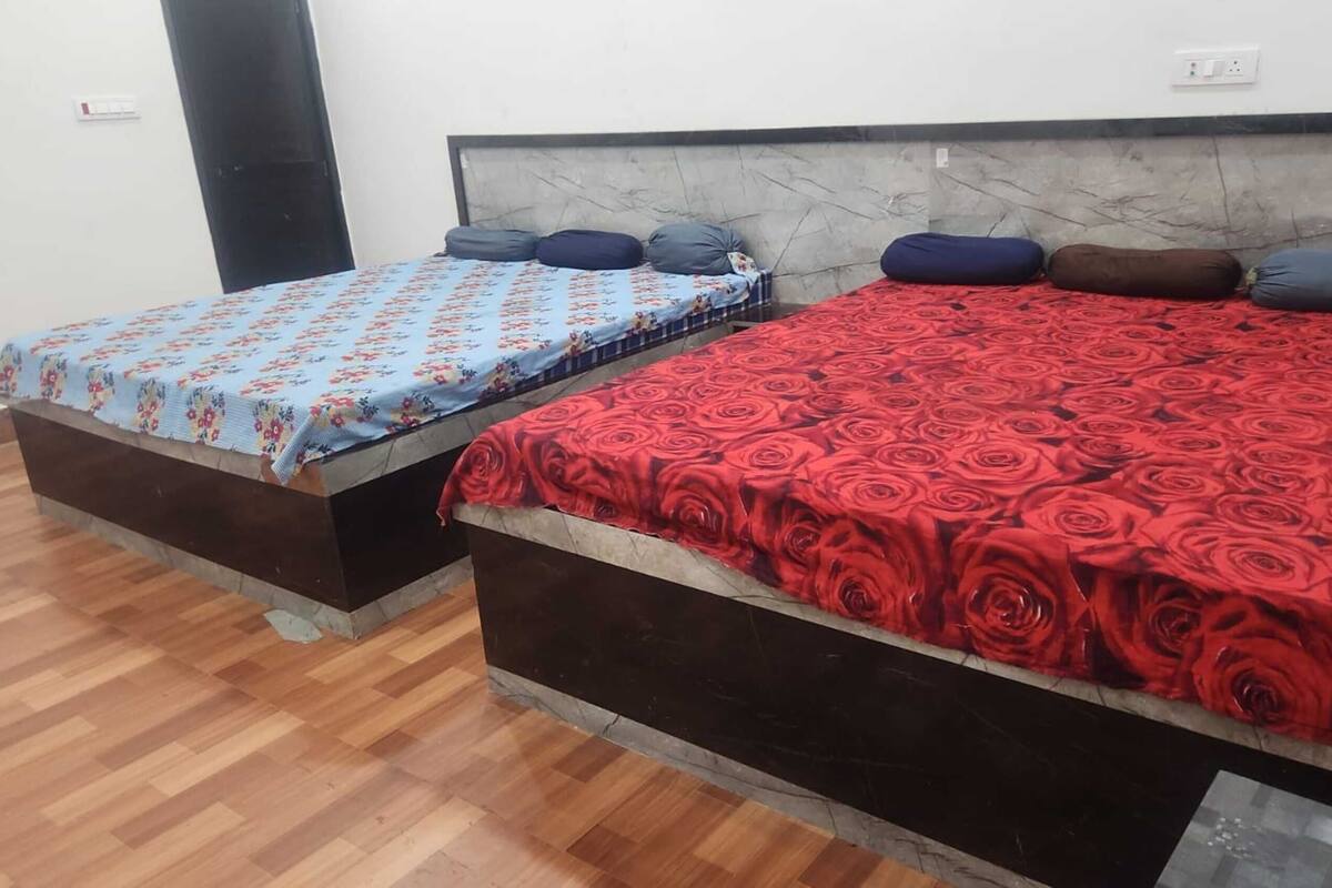 Two beds with distinct floral bedspreads, a marble headboard, and a wooden floor.