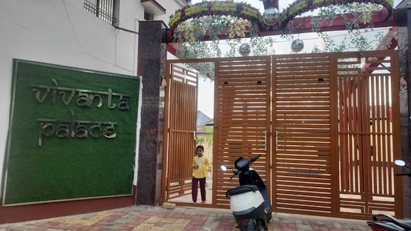 A gated entrance with a sign reading 'vivanta palace' and a scooter parked in front. - Vivanta Palace (Deoghar)