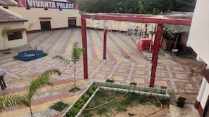 A courtyard with a tiled floor, a pergola, and a sign for 'Vivanta Palace.' - Vivanta Palace (Deoghar)