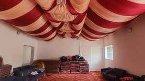 Una stanza con soffitto drappeggiato in rosso e beige, una pila di coperte e due divani.