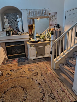 A living room with a fireplace, a staircase, and a large rug. - Cozy, with unique European settings close to strip (Las Vegas)