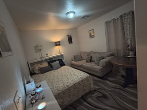 Una habitación de hotel con una cama, un sofá, una mesita y una lámpara.