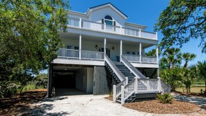 Ein zweigeschossiges Gebäude mit Balkon, Treppe und einer überdachten Garage.