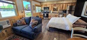 Ein gemütlicher Wohnraum mit Sofa, Bett, Esstisch und Küchenzeile.