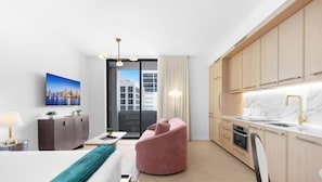A modern kitchen with wooden cabinets, a marble countertop, and a built-in oven. - Wynwood Studio | Rooftop Experience | Pool & Bar (Miami)