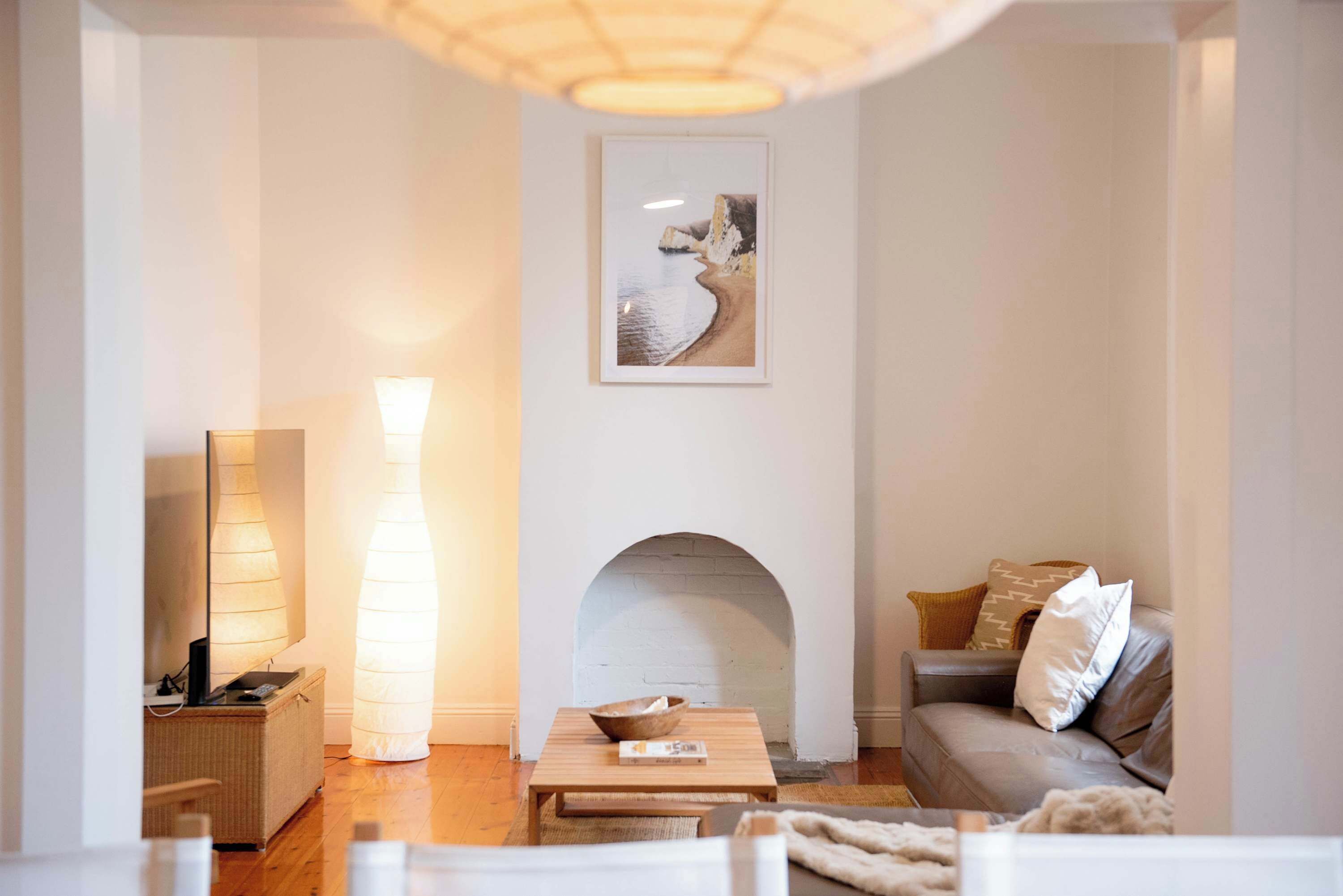 Una sala de estar con chimenea, un sofá, una mesa de centro y una lámpara.