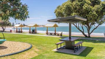 A beachside park with picnic tables, gazebos, and a clear view of the ocean.
