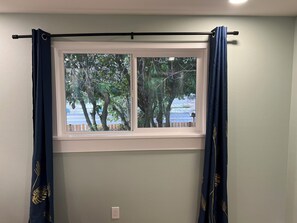 A window with a view of trees and a parking lot, a curtain rod, and a wall socket. - Harmony home - A Spacious 4-bedroom single family home with AC (Kirkland)