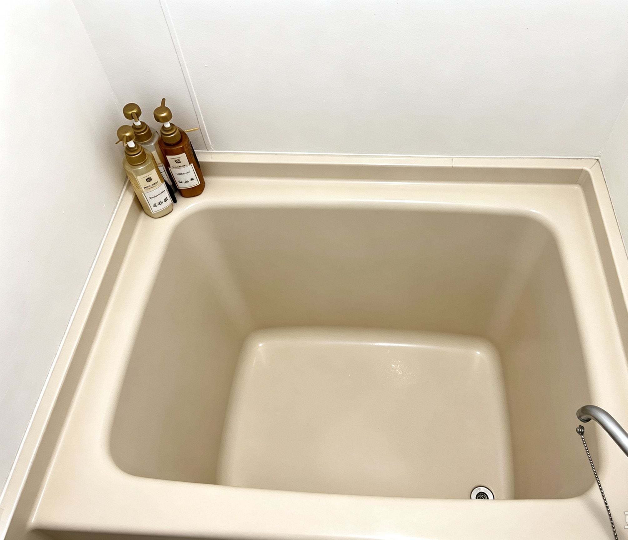A bathtub with a faucet and two bottles of liquid soap on the side.