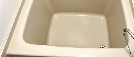 A bathtub with a faucet and two bottles of liquid soap on the side.