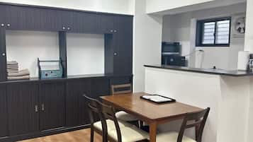 A modern kitchen with a dining table and chairs, built-in cabinets, and a window.