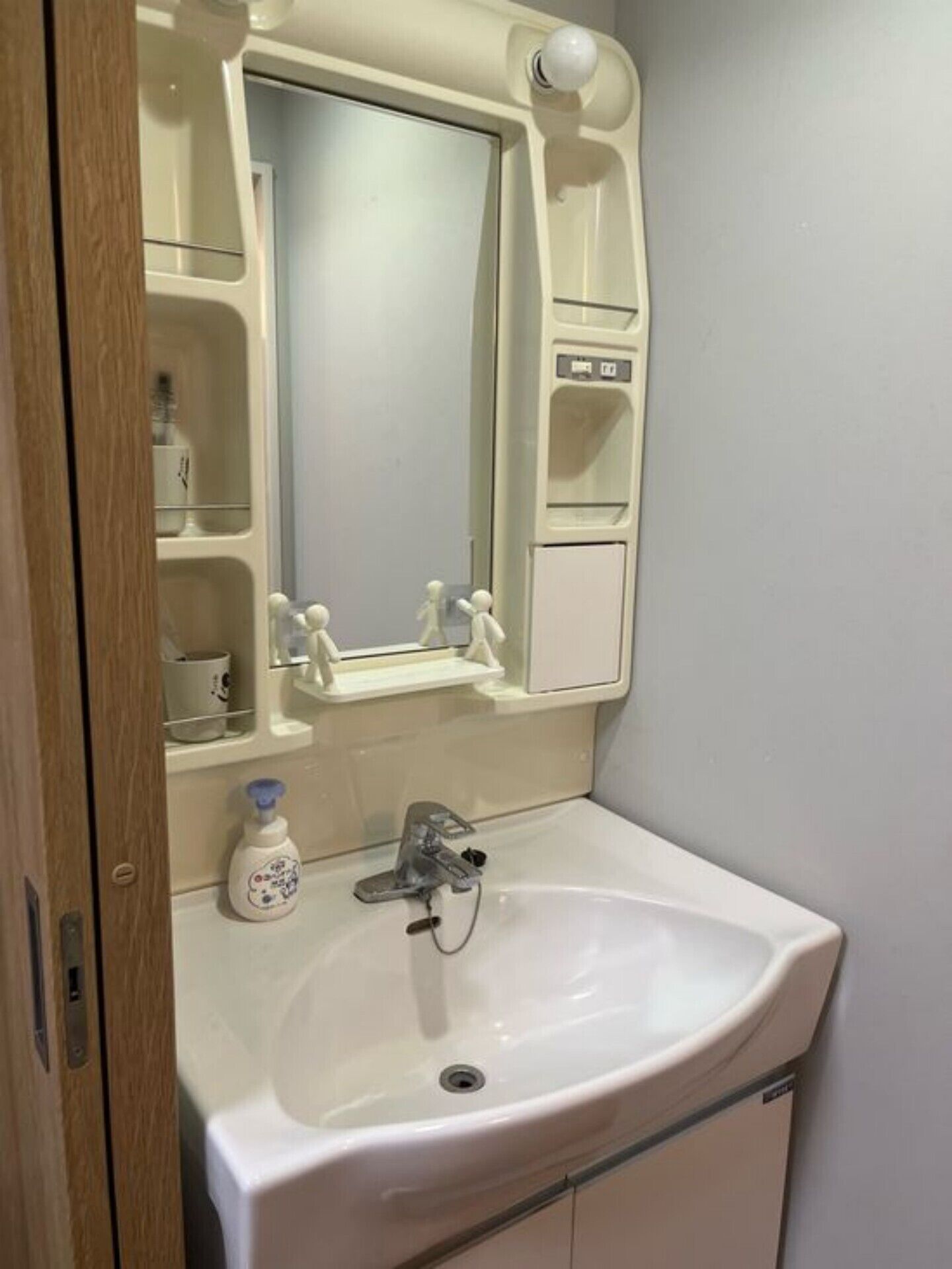 Un baño con un lavabo blanco, un espejo y un pequeño estante con artículos de aseo.