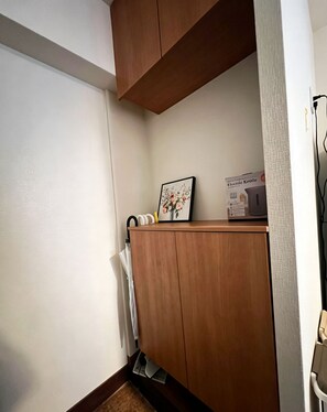 Rincón de una habitación con un armario de madera, un cuadro enmarco y una caja etiquetada 'Electric Kettle'.