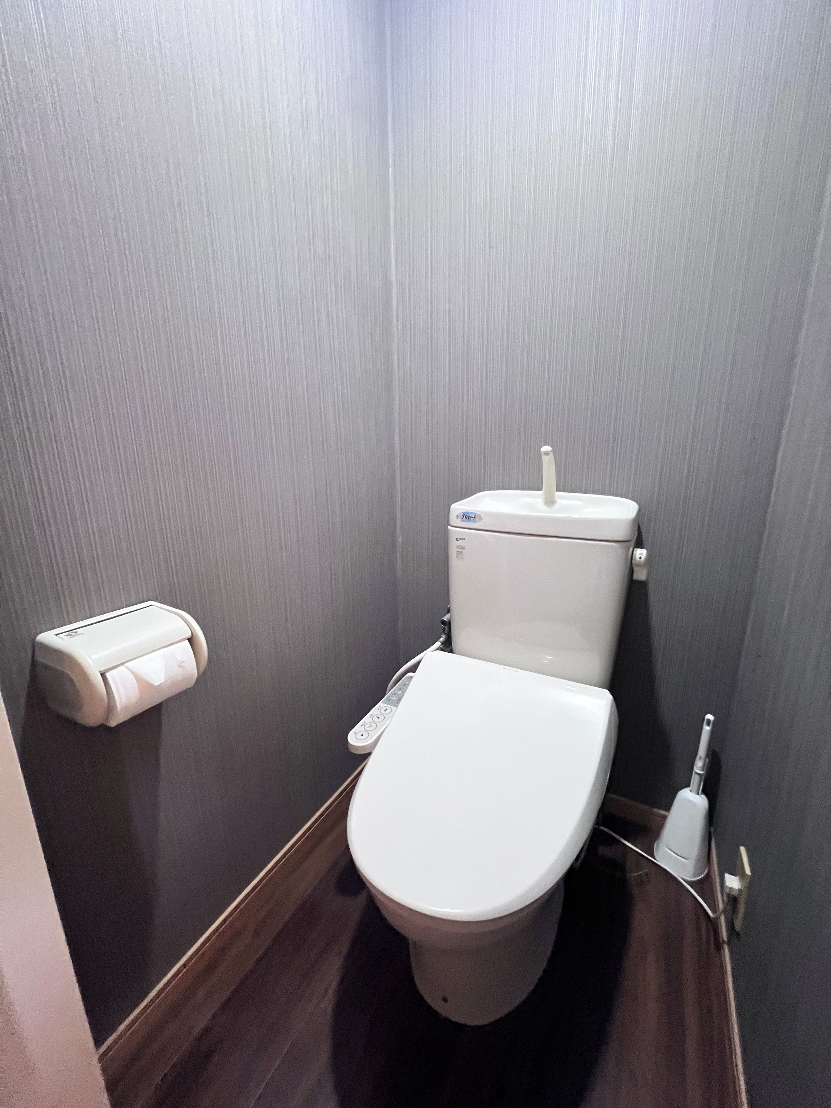 A small, compact bathroom with a toilet, a paper towel dispenser, and a hand dryer.