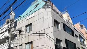 A multi-story building with a tiled facade, a bicycle parked outside, and a white van parked on the street. - GORO HOTEL (Tokyo)
