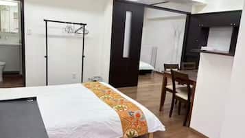 A hotel room with a bed, a desk, a chair, a wardrobe, and a bathroom visible through an open door.