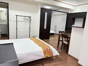 Habitación de hotel con cama, escritorio, silla, armario y baño visible a través de una puerta abierta.