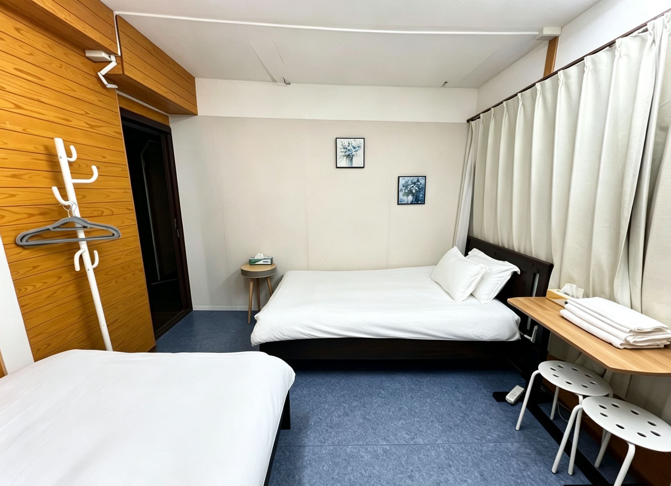 A hotel room with a bed, a bedside table, a chair, and a coat rack.