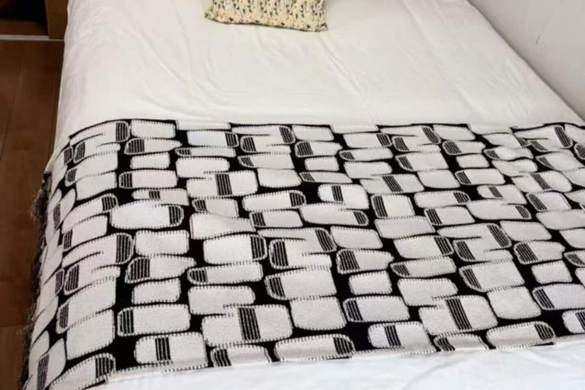 Una cama con una colcha estampada, un cojín floral y un cabecero de madera.