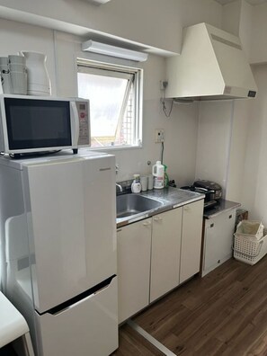 Una cocina compacta equipada con refrigerador, microondas, pileta y ventana.