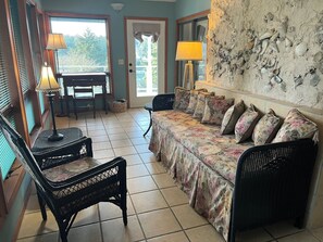 A room with a sofa, two chairs, a dining table, and a lamp.