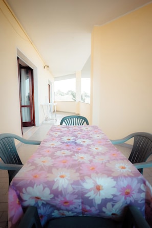Un balcone con tavolo e sedie, una porta e vista sull'esterno.