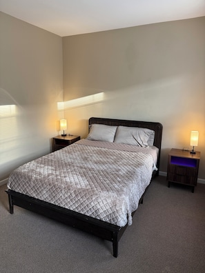 A bedroom with a bed, two bedside tables, and a nightstand with a lamp. - Paradise Lounge 3bd apartment in Central Chicago with AC & Balcony (Chicago)