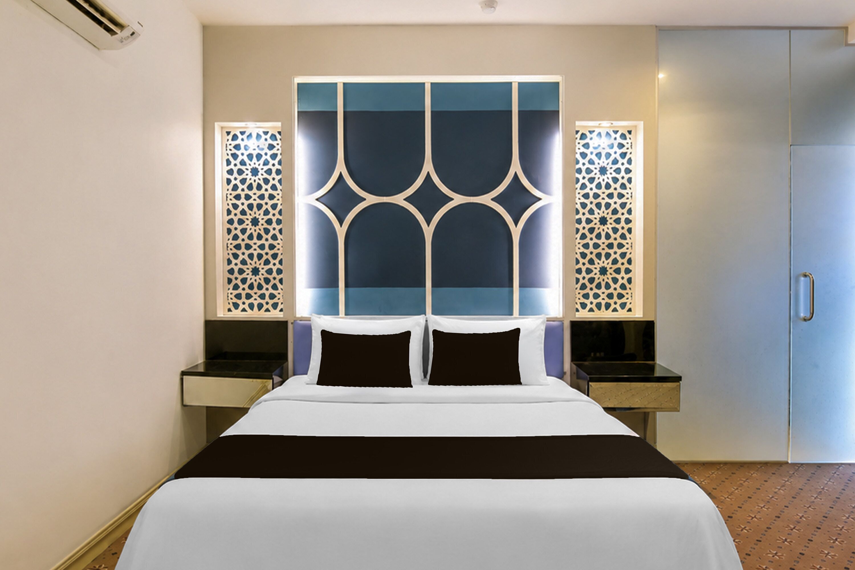 A hotel room with a bed, a nightstand, a wardrobe, and decorative wall panels.