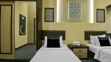 A hotel room with two beds, a nightstand, a mirror, and decorative wall art.