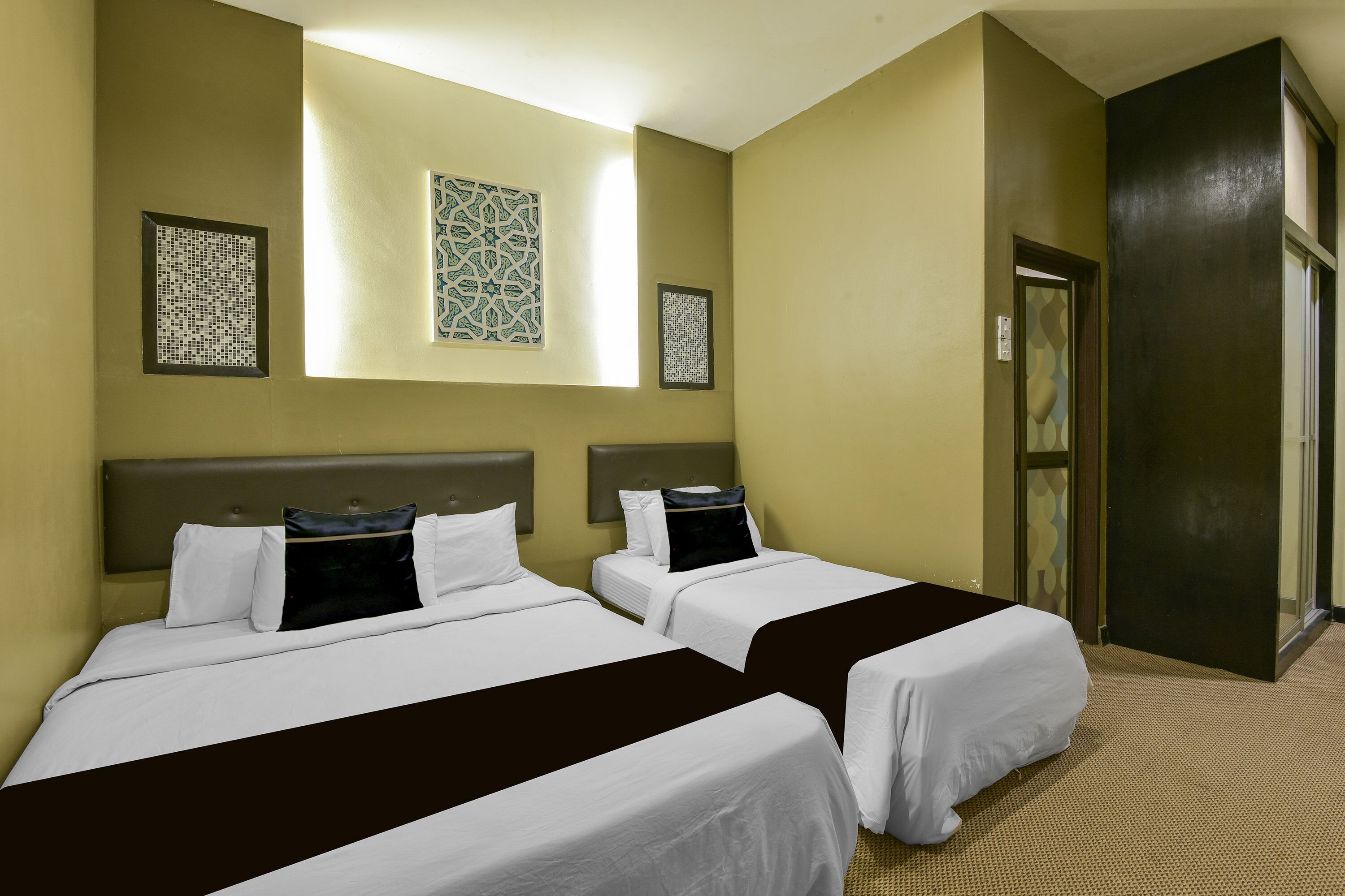 A hotel room with two beds, a headboard, a wall-mounted artwork, and a door.