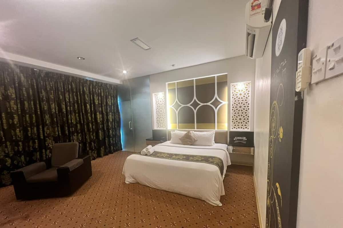 Hotellihuone, jossa on suuri sänky, sohva, kuviollinen matto ja koristeelliset seinäpaneelit.