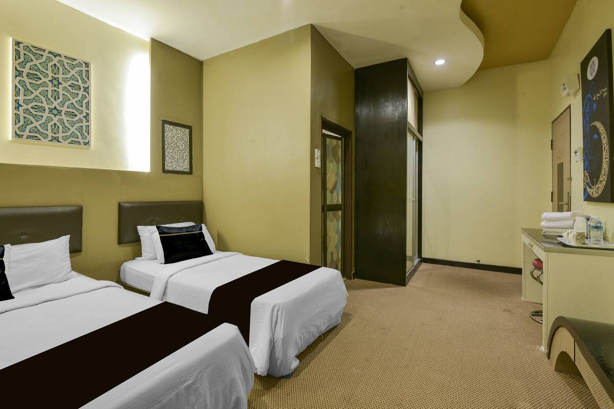 Ein Hotelzimmer mit zwei Betten, einem Schreibtisch und einer Badezimmertür.