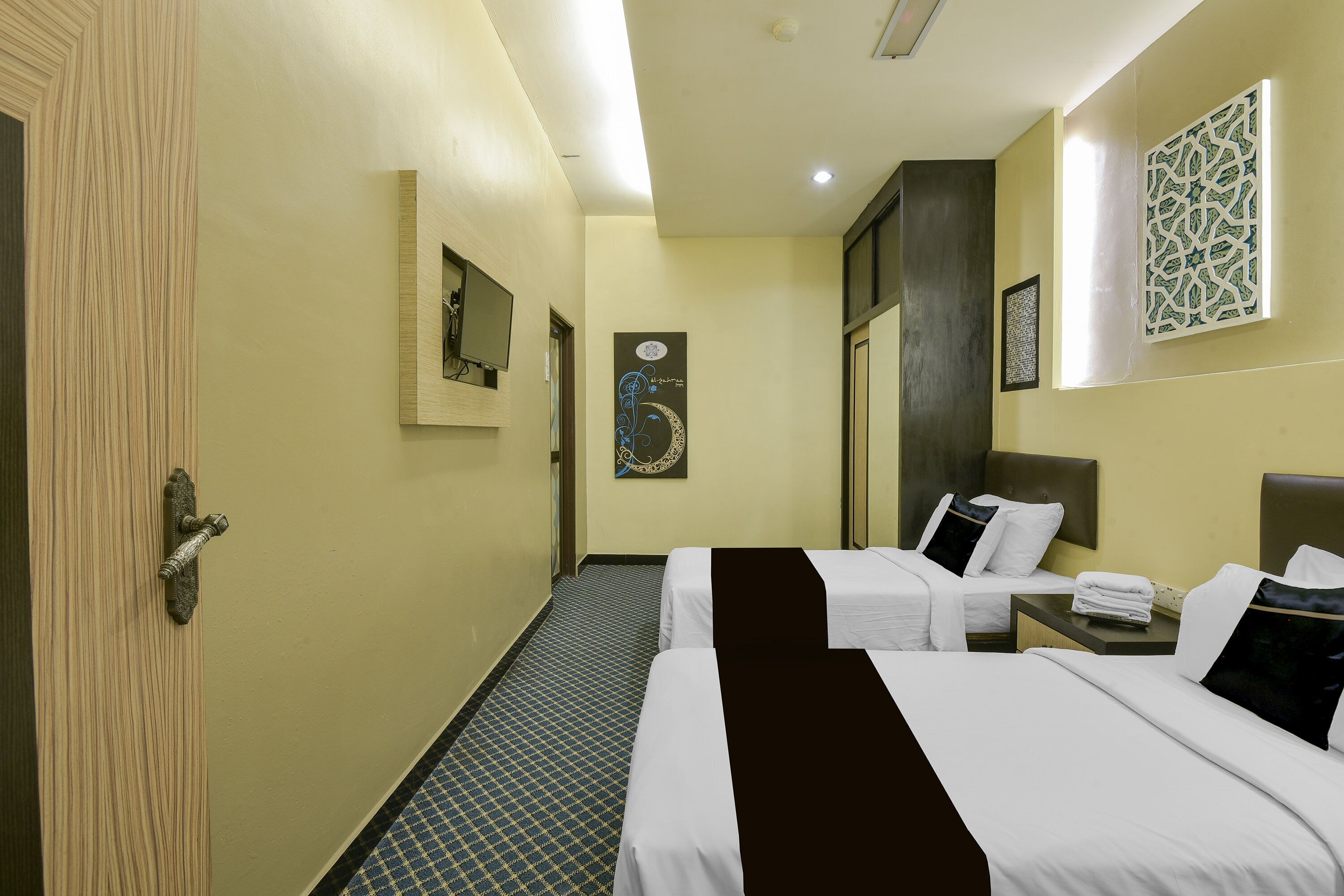 Ein Hotelzimmer mit zwei Betten, einem kleinen Tisch, einem Spiegel und einem gemusterten Boden.