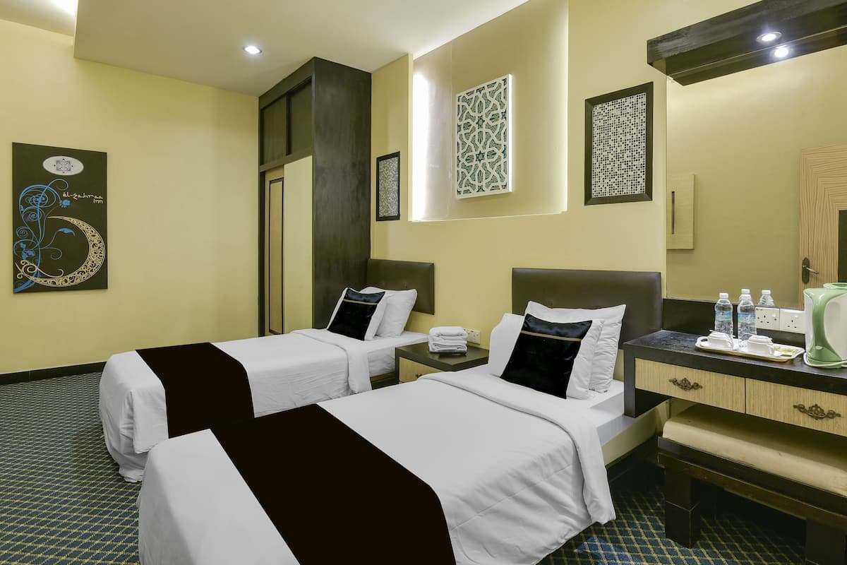 Ein Hotelzimmer mit zwei Betten, einem Schreibtisch mit Spiegel und Bildern an den Wänden.