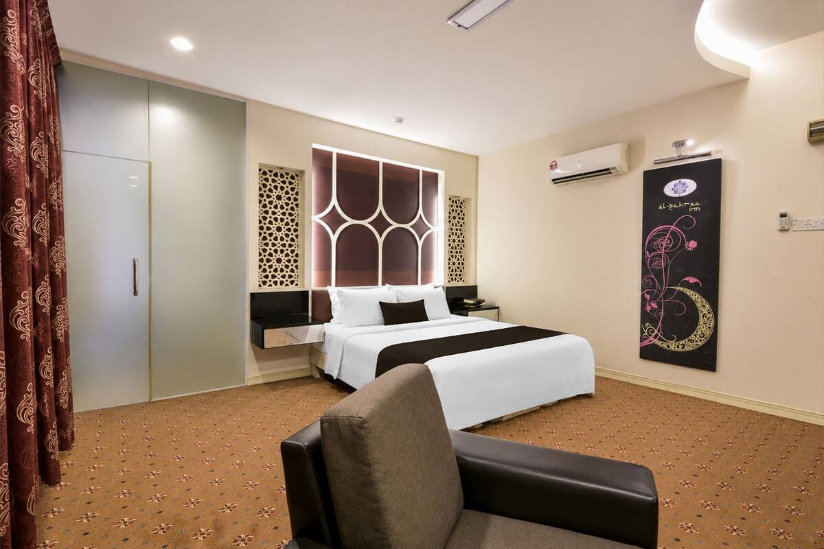Ein Hotelzimmer mit Bett, Stuhl, Kleiderschrank, einer Wandverkleidung und einer Klimaanlage.