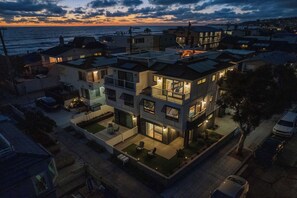 Ein modernes Mehrfamilienhaus mit Dachterrasse, großen Fenstern und Blick aufs Meer.