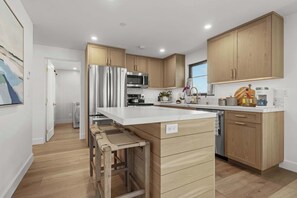 Eine moderne Küche mit Holzausstattung, Edelstahlgeräten und einer zentralen Kochinsel.