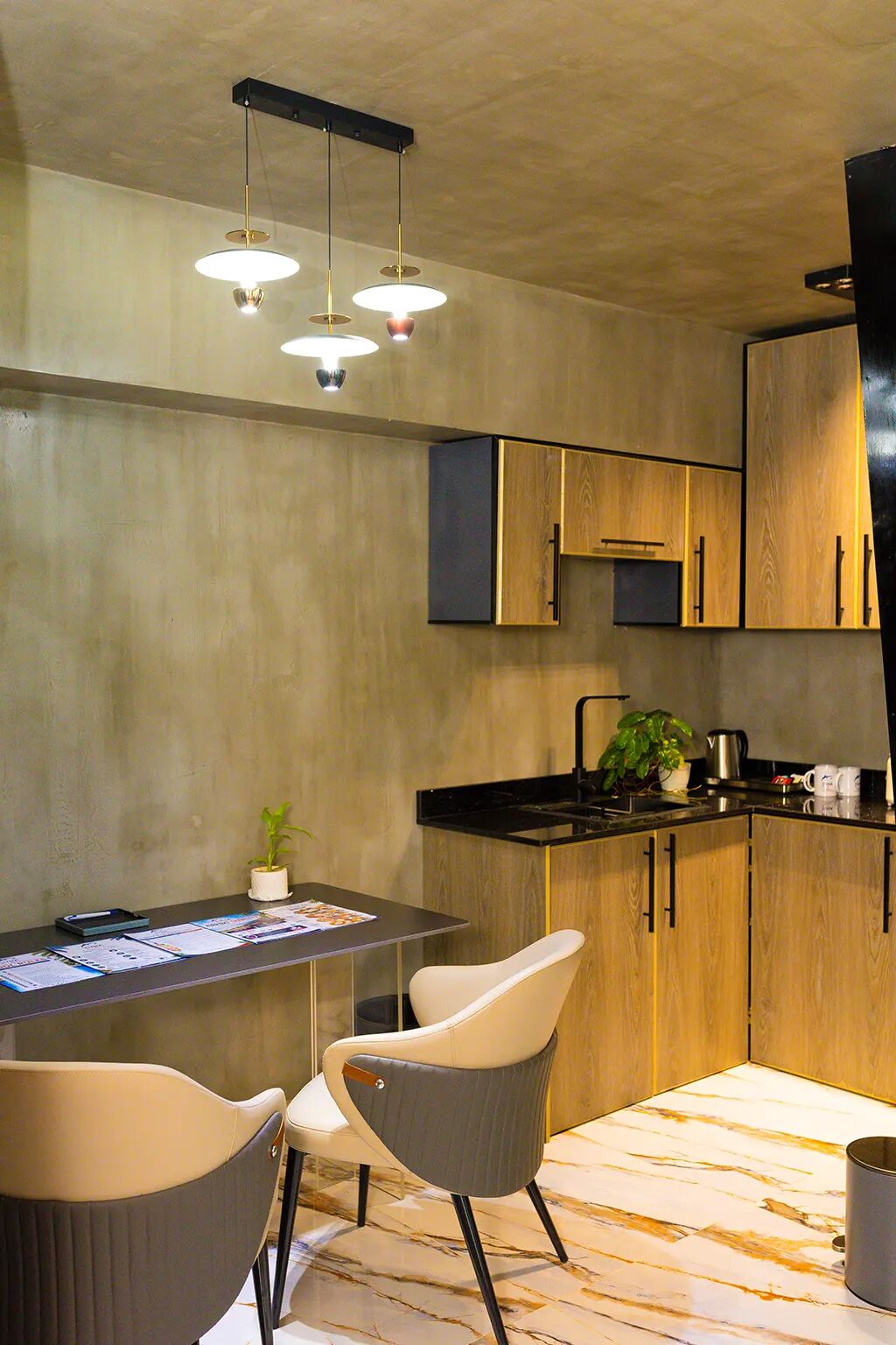A modern kitchen with wooden cabinets, a black countertop, and pendant lighting.