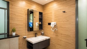 Un baño moderno con pared de madera, un lavamanos, un espejo, un secador de pelo y un televisor.