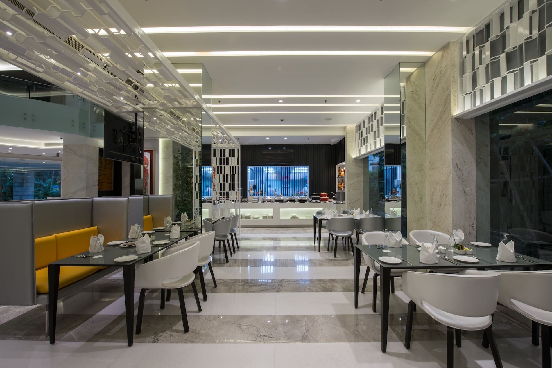 En modern restauranginteriör med glasväggar, vita stolar och en central matplats.