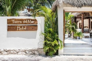 A wooden sign for Tierra del Mar Hotel with a stone wall and tropical plants. - Tierra del Mar (Isla Holbox)