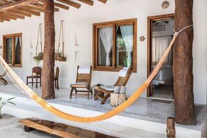 A hammock, wooden chairs, a small table, and a window with curtains. - Tierra del Mar (Isla Holbox)