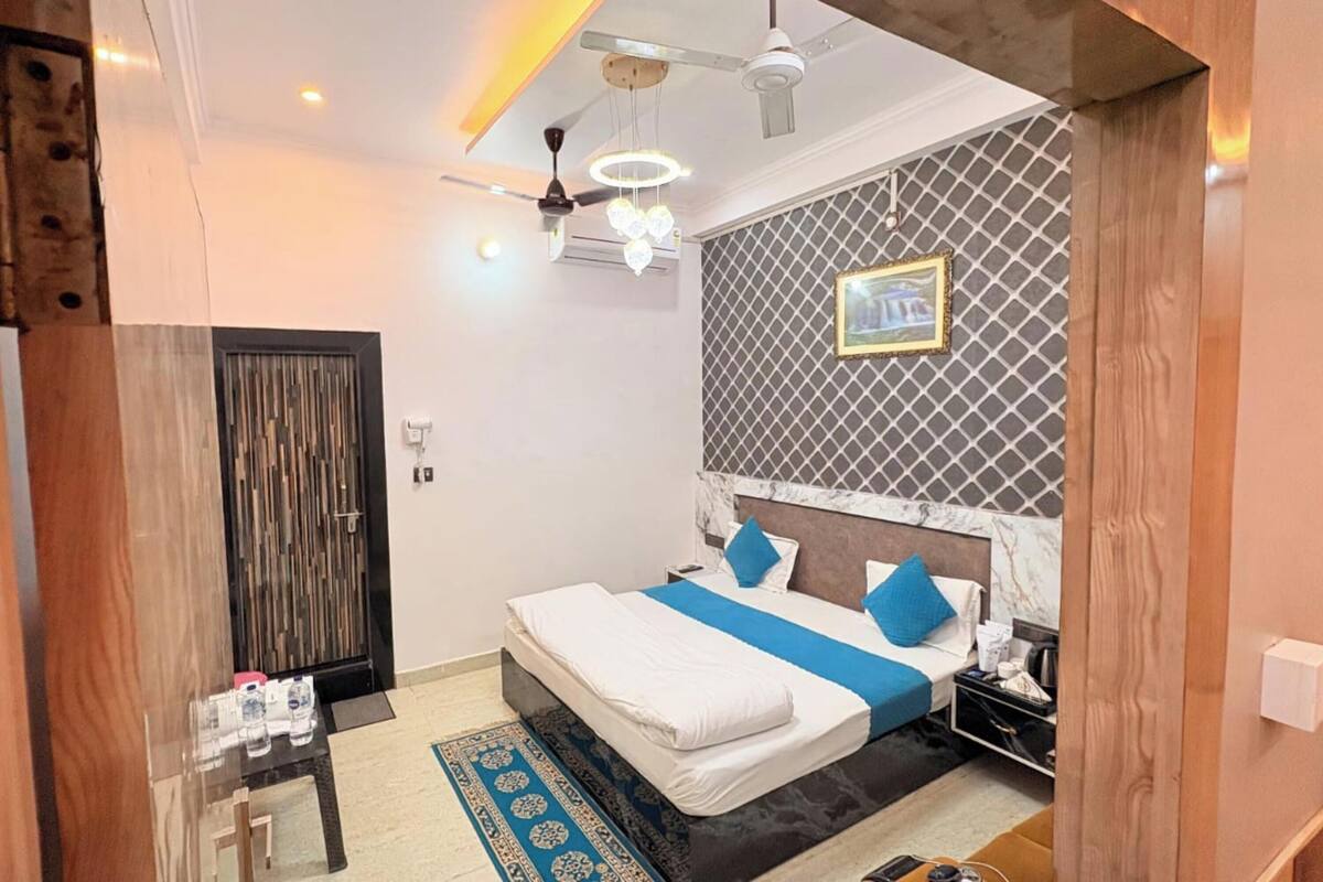 A hotel room with a bed, bedside table, and a wall-mounted picture.