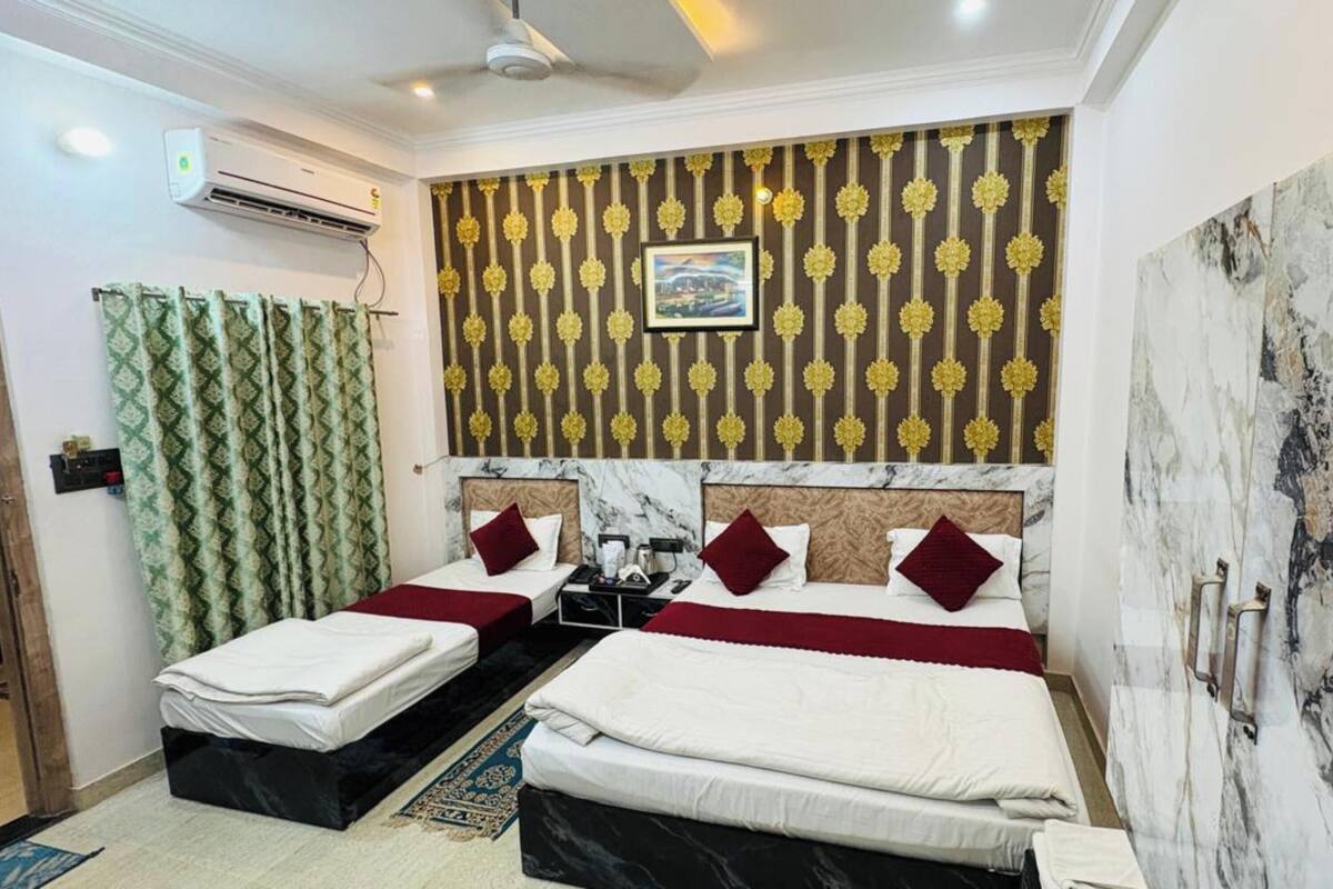 A hotel room with two beds, a marble wall, a patterned wallpaper, and a ceiling fan.