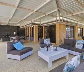 Un espacio exterior amueblado con sofás, una mesa de centro y un comedor.