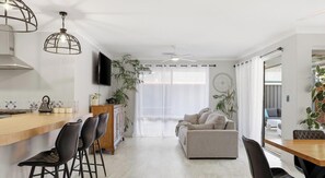 Een moderne keuken met een bar, een eethoek met stoelen, een bank en een tv aan de muur.