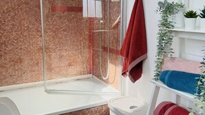 A bathroom with a glass-enclosed shower, a white sink, a white toilet, and a shelf with towels and plants. - Central Apartment in London Bridge! (London)