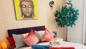 A neatly made bed with patterned bedding, a Buddha painting on the wall, a potted plant, and a bedside table with a lamp and a book. - Central Apartment in London Bridge! (London)
