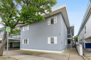A grey building with white shutters, a visible number '3834', and a tree in front.